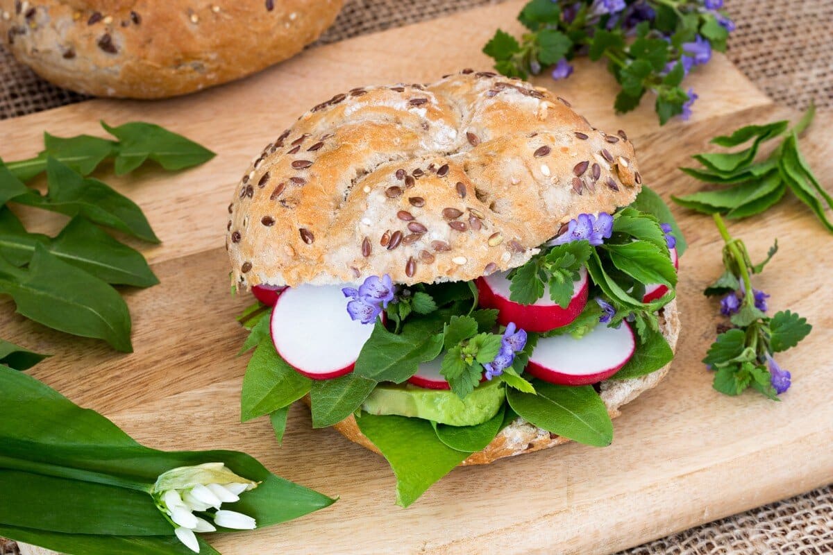 Belegte Brötchen mit Avocado, Bärlauch und essbaren Blüten zum Frühstück