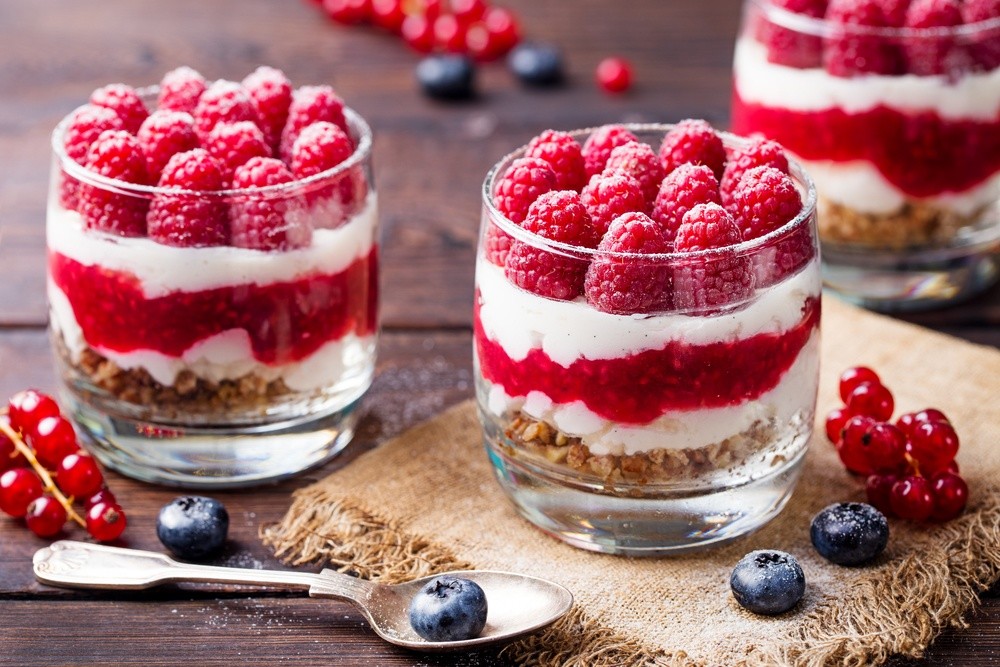 Dessert im Glas mit Quark, Keksen, Sahne und Himbeeren