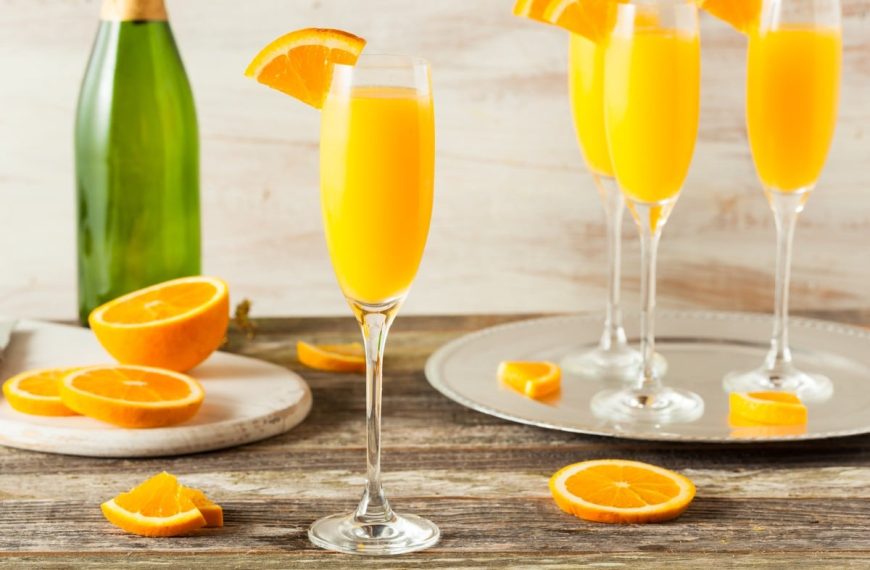Einfacher Cocktail aus Orangensaft, Sekt und frischen Orangen