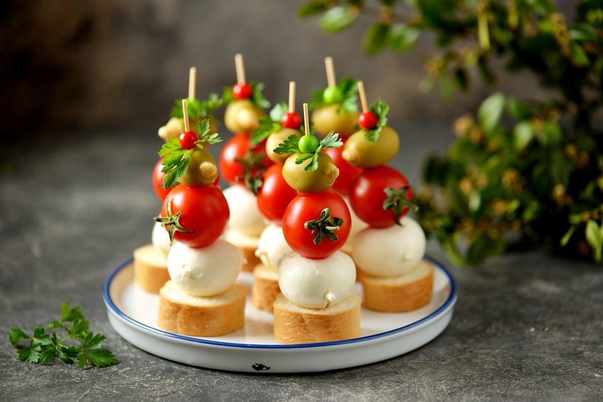 Fingerfood mit Tomaten, Mozzarella und Oliven auf Baguette