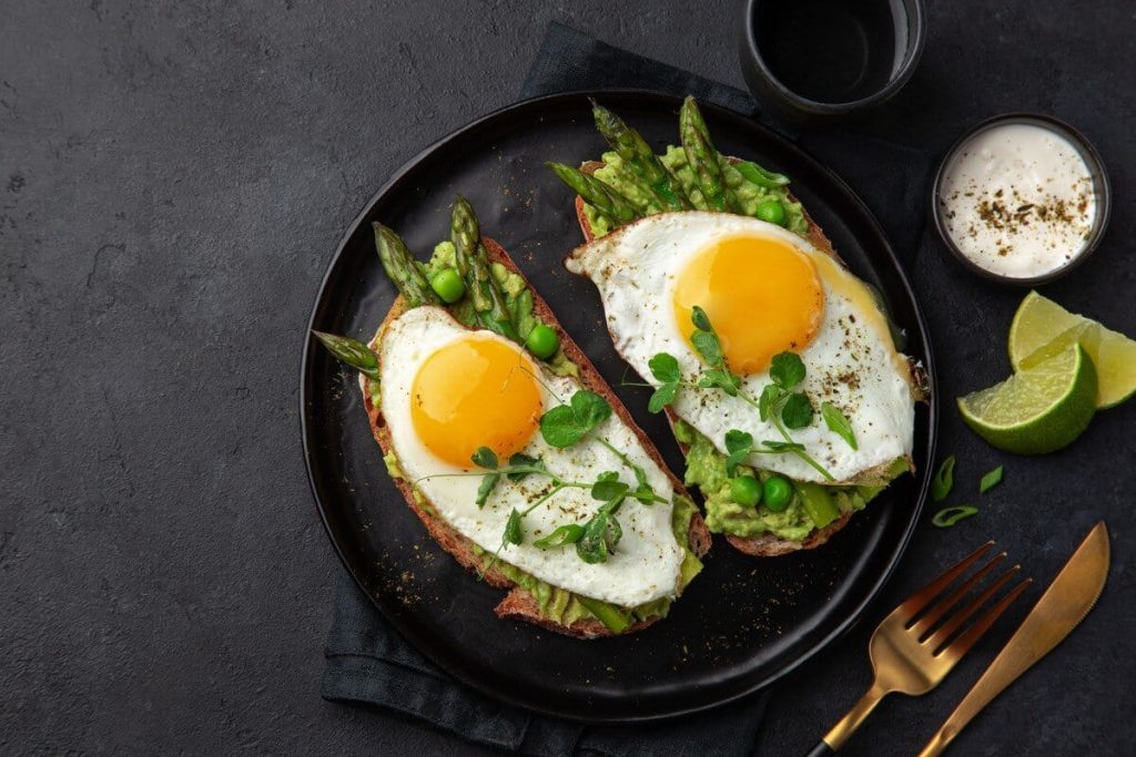 Frühstücksei auf Avocado Brot mit grünem Spargel