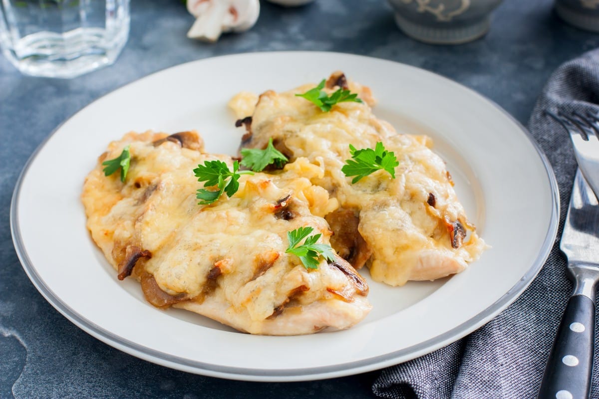 Gebackene Hähnchenschnitzel mit Champignons und Käse im Ofen