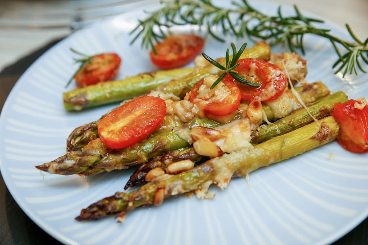 Grüner Spargel mit Tomaten, Parmesan und Pinienkernen im Backofen