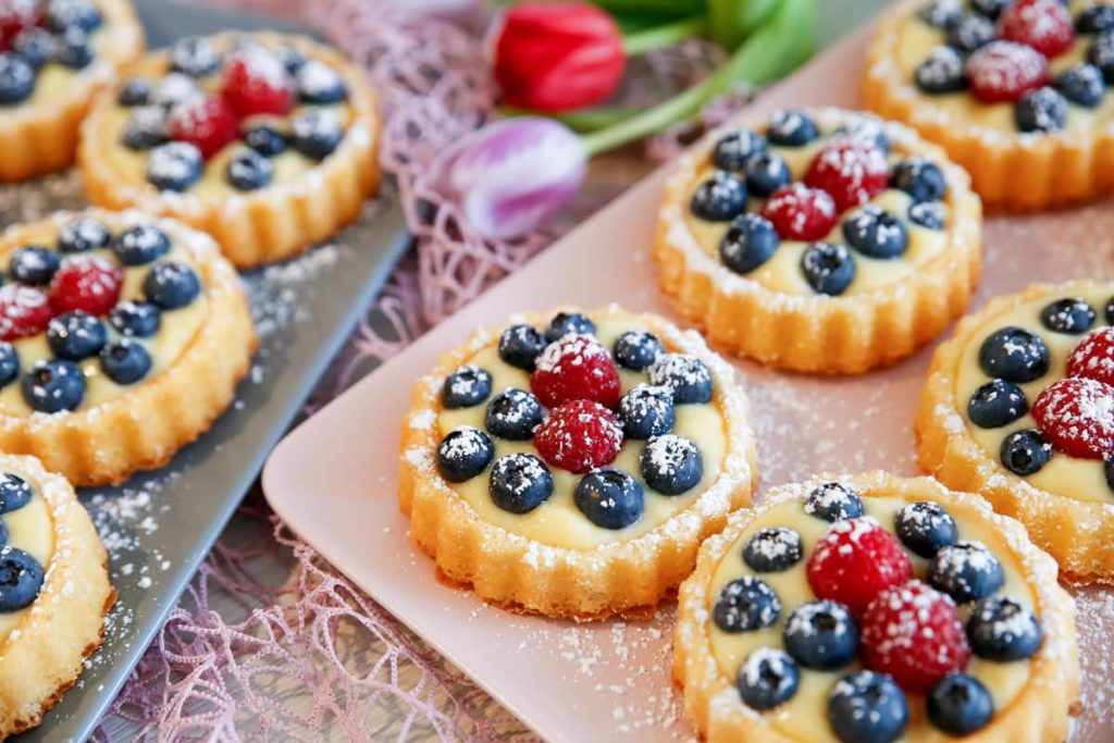 Kleine Obsttörtchen aus Biskuit mit Beeren und Pudding