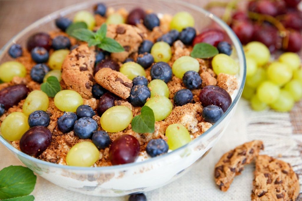 Leckeres Schichtdessert mit Weintrauben, Cookies und Heidelbeeren