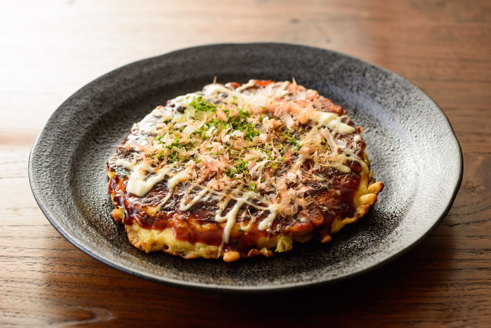Okonomiyaki japanischer Pfannkuchen mit Weißkohl und Speck