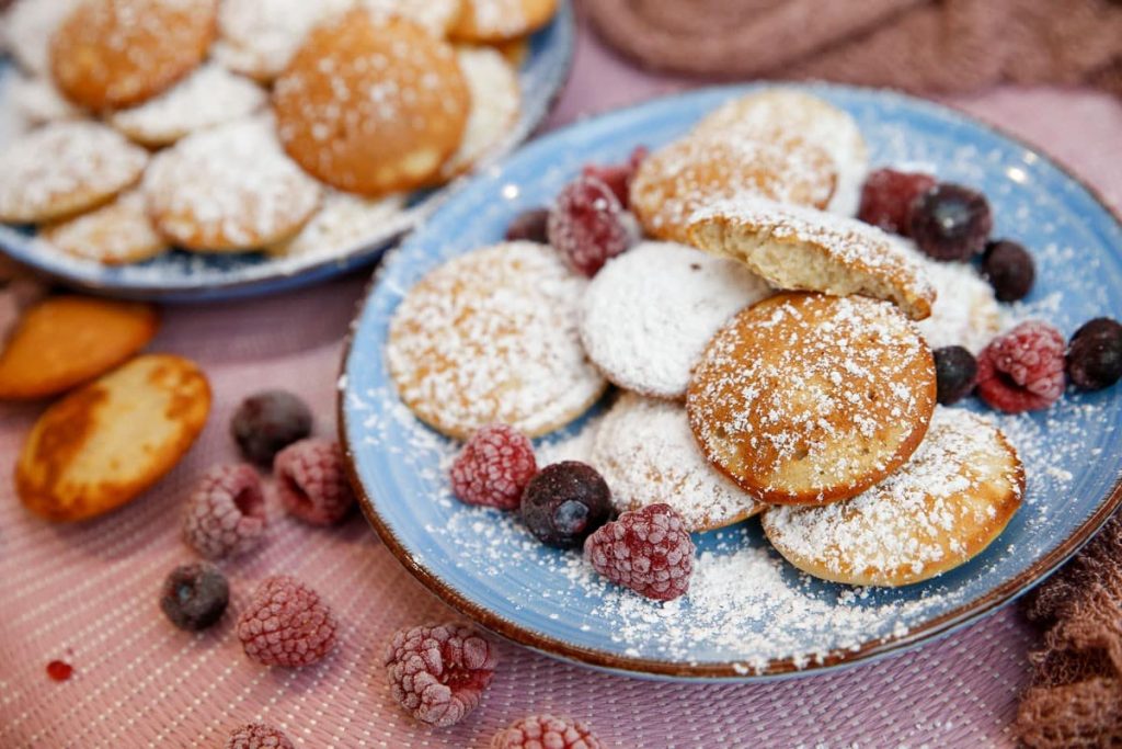 Poffertjes aus Hefeteig mit Puderzucker und Beeren