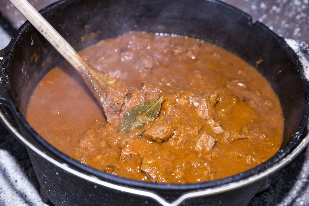 Rindergulasch mit Gemüsezwiebeln und Rotwein im Kessel