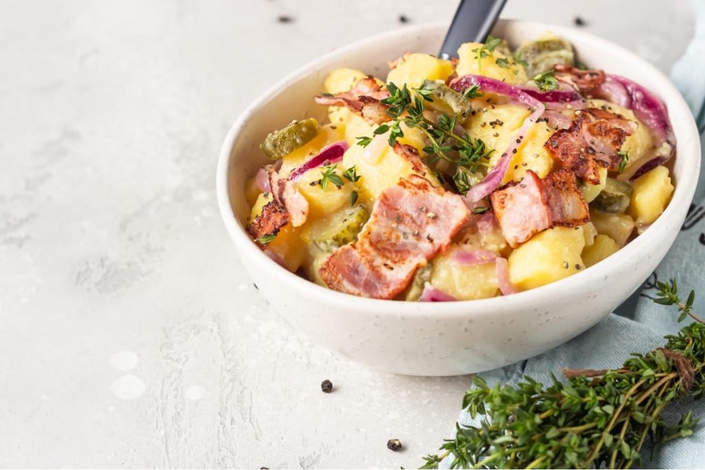 Schmackhafter Kartoffelsalat mit Essiggurken und Speck