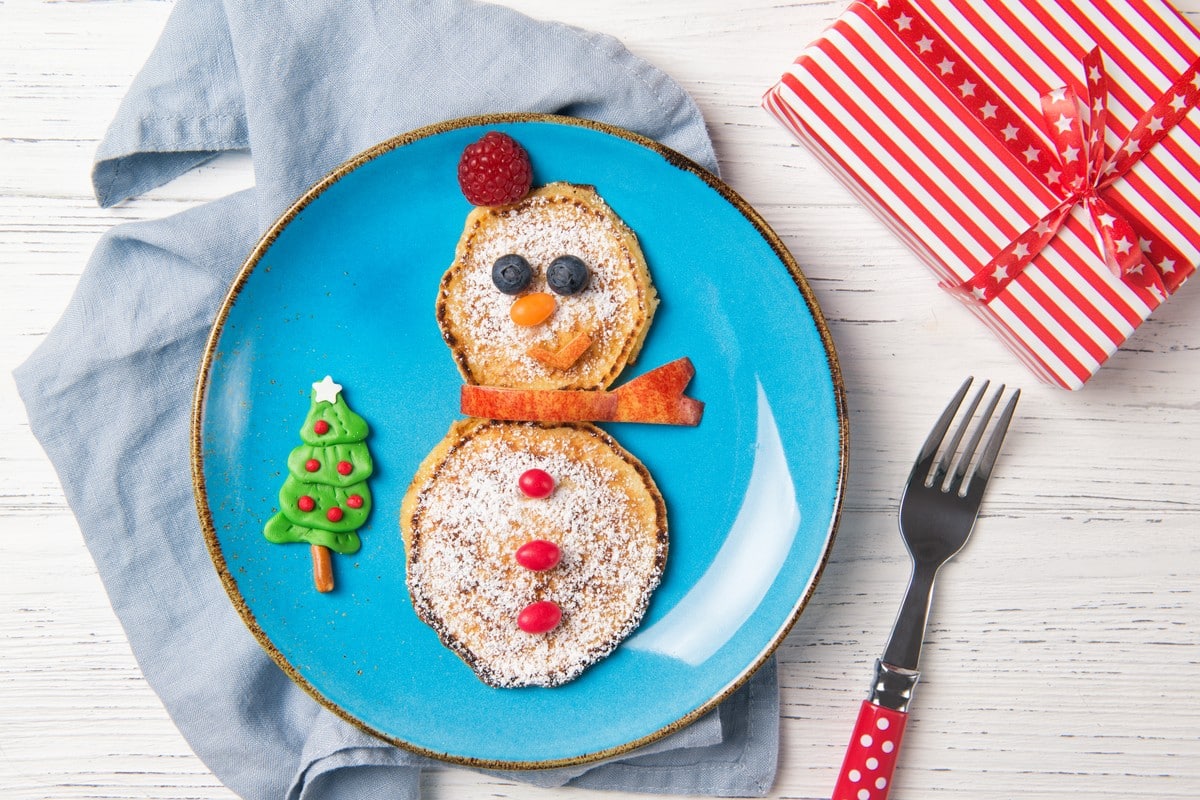 Schneemann Pancakes mit Puderzucker und Obst zu Weihnachten