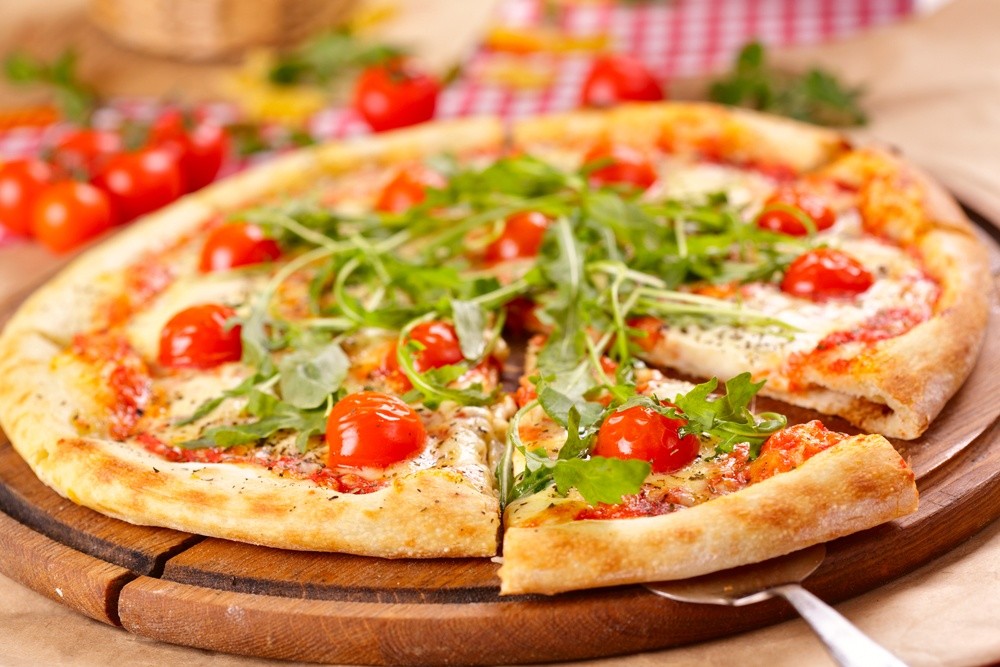 Selbstgemachte Pizza mit Rucola und Tomaten