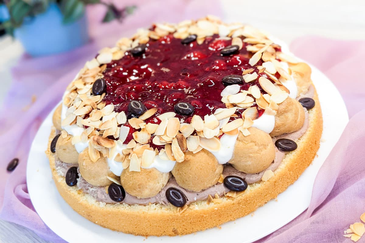 Traumhafte Sahnetorte mit Windbeuteln und roten Grütze