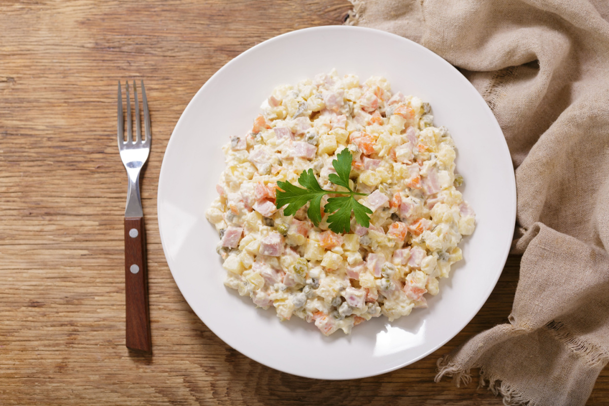 Cremiger Salat Olivier mit Kartoffeln und Schinken