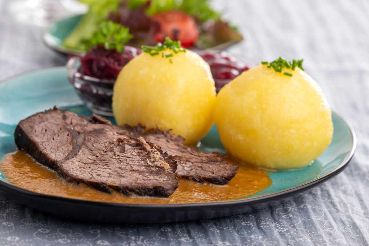 Traditioneller Sauerbraten mit dunkler Soße und Kartoffelklößen