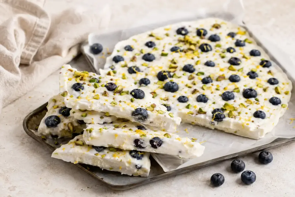 Frozen Yogurt Bark mit Heidelbeeren, Pistazien und Zitrone auf einem Backblech