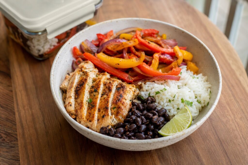 Hähnchen-Fajita-Bowl mit Reis, Paprika, schwarzen Bohnen und Limette